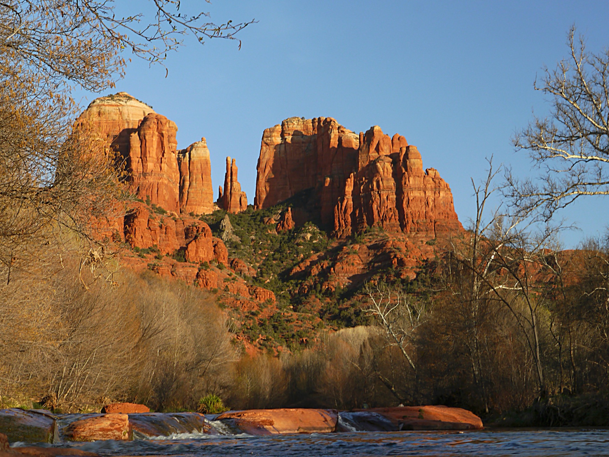 Cathedral Rock red sandstone formation in Sedona, Arizona at sunset, with creek reflection in the foreground